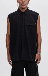 Camisa sin mangas de corte oversize, color negro, confeccionada en tejido twill. Presenta cuello clásico, cierre frontal oculto y un bolsillo tipo cargo con solapa y remaches metálicos en el pecho.