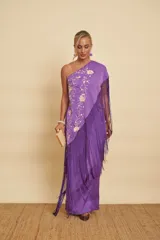 Vestido largo morado de un solo hombro, con detalles bordados florales en tono crudo y un gran mantón con flecos largos del mismo color.