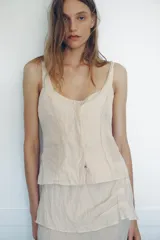 Top de viscosa con diseño efecto arrugado, escote redondo, tirantes finos y cierre frontal con botones ocultos.