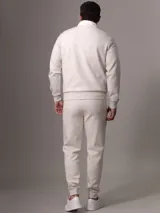 Buzo color crema de Calvin Klein confeccionado en mezcla de algodón y poliéster. Presenta cuello alto con media cremallera negra, puños y dobladillo con punto canalé.