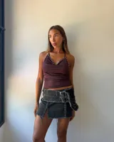 Minifalda de jean color negro con efecto desgastado, diseño de tajo frontal y cinturón integrado con hebilla metálica grande.