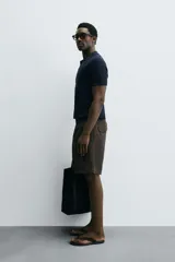 Polo de manga corta, color celeste pálido, con cuello solapa y abertura frontal en V. Tejido de punto con textura acanalada vertical.