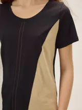 Remera de manga corta con diseño colorblock en tonos blanco, negro y beige, escote redondo y costuras verticales decorativas en el centro.