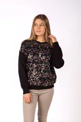 Sweater de punto negro con frente decorado con lentejuelas multicolor, cuello redondo y mangas largas con puños acanalados.