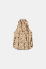 Top de cuello halter con diseño sin mangas, confeccionado en tela fluida con estampado de manchas abstractas. Presenta un cierre en la espalda con abertura y botones.
