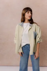 Camisa lila de calce relajado y manga larga, con cuello clásico, puños y bolsillo delantero en denim contrastante. Cierre frontal con broches metálicos.