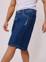 Bermuda de jean azul oscuro con logo Rusty bordado en blanco en la pierna izquierda.