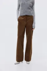 Pantalón de corte bootcut confeccionado en gamuza color marrón. Presenta cierre frontal con botón oculto, bolsillos laterales al bies y costuras decorativas horizontales sobre las rodillas.