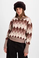 Sweater de punto con diseño de rombos en tonos marrones, beige y crema. Presenta cuello redondo, mangas largas con puños anchos acanalados y diseño de rayas en los puños y el ruedo.