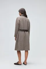 Tapado largo de lana fina con diseño de espiga en tonos beige. Presenta cuello camisero y solapas de bolsillos en cuero color suela, con cierre frontal de botones a tono.