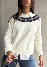 Sweater de punto color natural con cuello redondo y detalle de guarda tejida en la parte superior del pecho. Presenta mangas largas con puños acanalados y un diseño de corte recto.