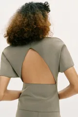 Top de cuello redondo y manga corta, con diseño liso y detalle de abertura (cut out) en la espalda.