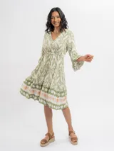 Vestido midi verde y crudo con estampado geométrico, escote en V con botones frontales, mangas tres cuartos acampanadas y falda con volados en capas.