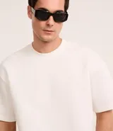 Remera de corte boxy con cuello redondo y mangas cortas, confeccionada en tejido de malla pesada con textura gomosa.