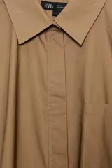 Camisa de corte amplio confeccionada en algodón, con cuello solapa, manga larga con puños y cierre frontal con botones ocultos bajo solapa. Presenta un bolsillo frontal en el pecho.