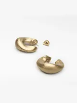 Par de aros tipo argolla de diseño irregular y orgánico, con acabado dorado mate. Cierre tipo broche.