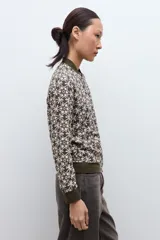 Campera bomber verde oliva con estampado geométrico en blanco, cuello, puños y cintura elásticos.