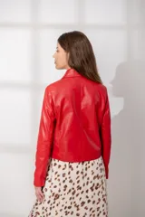 Chaqueta de cuero ovino en color rojo, con corte recto, cuello clásico, hombros definidos y cierre frontal con cremallera metálica. Presenta bolsillos laterales con cierre y puños con cremallera.