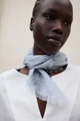 Blusa de lino blanca de corte amplio, con escote en V, mangas largas y puños con abertura y lazo.