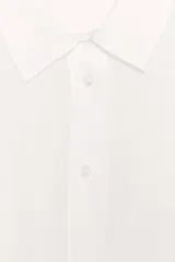 Camisa de color mostaza, con cuello solapa, manga corta y bajo recto. Cierre frontal con botones.