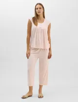 Pijama compuesto por remera sin mangas con escote redondo, botones frontales y detalle de puntilla, acompañado de un pantalón capri con cintura elástica. Presenta un estampado floral en tonos rosados sobre base gris.