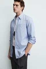 Camisa de corte regular fit confeccionada en tejido de algodón, con diseño de rayas verticales en tonos azules. Presenta cuello abotonado, manga larga con puños abotonados, cierre frontal de botones y un bolsillo en el pecho.