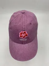 Gorro de béisbol color bordó con efecto lavado y bordado frontal de una flor de hibisco y la palabra 'hibiscus'.