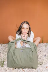 Bolso deportivo tipo duffel bag de nylon color verde oliva, con asas de mano y correa ajustable para llevar al hombro.