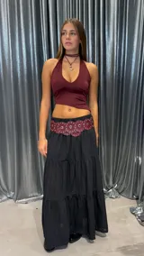 Pollera larga negra, con corte amplio y volados en capas. Presenta textura acanalada o plisada fina.