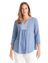 Blusa de modal texturizado en color azul, con cuello a la base y escote en V. Presenta un panel frontal decorado con apliques circulares nacarados y mangas tres cuartos.