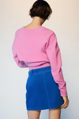 Falda mini de pana azul, con diseño de cinco bolsillos, cierre frontal con cremallera y botón.