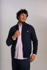 Cardigan de punto color azul marino, con cuello alto, cierre frontal completo y puños acanalados. Presenta el logo de la marca bordado en el pecho.