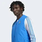 Chaleco azul con cierre frontal, bolsillos con cremallera y diseño reversible. Incluye logo de Adidas y escudo del Real Madrid bordado en el pecho.