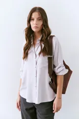 Camisa blanca de manga larga con cuello clásico y botones frontales.