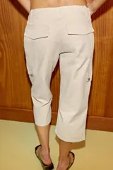 Pantalón capri de tiro medio con bolsillos cargo laterales, cierre frontal con cremallera, botón metálico y cordón ajustable en la cintura.