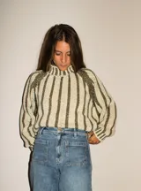 Sweater de tejido de punto en lana merino, con diseño de rayas verticales en contraste. Presenta cuello alto, mangas largas con puños ajustados y un corte holgado que aporta comodidad y elegancia.