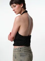 Top negro con escote halter, confeccionado en tejido elastizado con pequeños apliques brillantes distribuidos por toda la prenda.