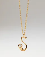 Collar de oro con dije de letra S que incluye una circonia incrustada en el extremo inferior, suspendido de una fina cadena de eslabones.