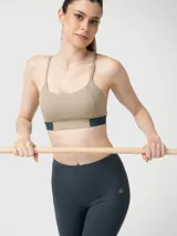 Top deportivo de sujeción media con diseño bicolor, presenta una base en color beige y una banda elástica inferior en color gris oscuro. Confeccionado en tejido suave y elástico con tecnología Aloe Vera.