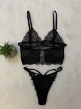 Conjunto de lencería de encaje negro compuesto por un bralette tipo crop top con tirantes ajustables y una bombacha colaless con tiras laterales decorativas.