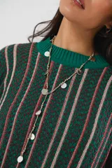 Sweater verde esmeralda de cuello redondo y manga larga, con terminación acanalada en puños y ruedo. Presenta tajos laterales y diseño de rayas verticales en tonos blanco y rosa.