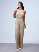 Enterito largo de gasa lurex plisada color dorado, con escote halter, cintura elastizada con punto smock, abertura en la espalda con cierre invisible y forro interno a tono.