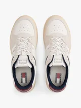 Zapatillas de corte bajo Tommy Jeans, confeccionadas en una combinación de cuero y ante en tonos blanco, beige y burdeos. Presentan suela cupsole de goma en color crema, cordones moteados y el logo de la marca en el lateral.