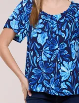 Blusa de poliéster azul con estampado botánico y floral, de silueta holgada y fluido diseño. Cuenta con escote redondo elastizado con frunces y mangas cortas amplias.