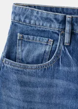 Jeans de denim azul de corte wide leg y tiro medio, con diseño clásico de cinco bolsillos y cierre frontal con botón y cremallera.