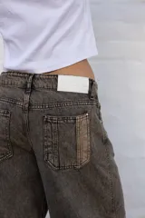 Jean de mujer color gris con efecto acid wash, de corte recto y tiro alto. Incluye bolsillos traseros y etiqueta de marca blanca en la cintura.