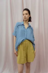 Short blanco de calce relajado con cintura elástica y lazo regulable. Presenta bolsillos amplios con ribete interior de color naranja neón.