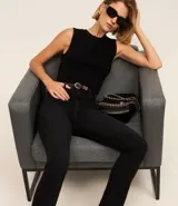 Pantalón de jeans negro, corte slim, con cintura media, trabillas en la cintura, bolsillos delanteros y traseros, y abertura en el ruedo.