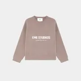 Suéter de punto grueso color marrón topo, con corte relajado y ligeramente corto. Presenta cuello redondo y puños acanalados, con el logo de la marca y la frase 'curated by ben ice' en jacquard blanco en el frente.