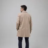 Gabardina impermeable color beige con cierre frontal de botones, cuello clásico y ajuste en las mangas. Cuenta con interior forrado a cuadros y bolsillos internos.
